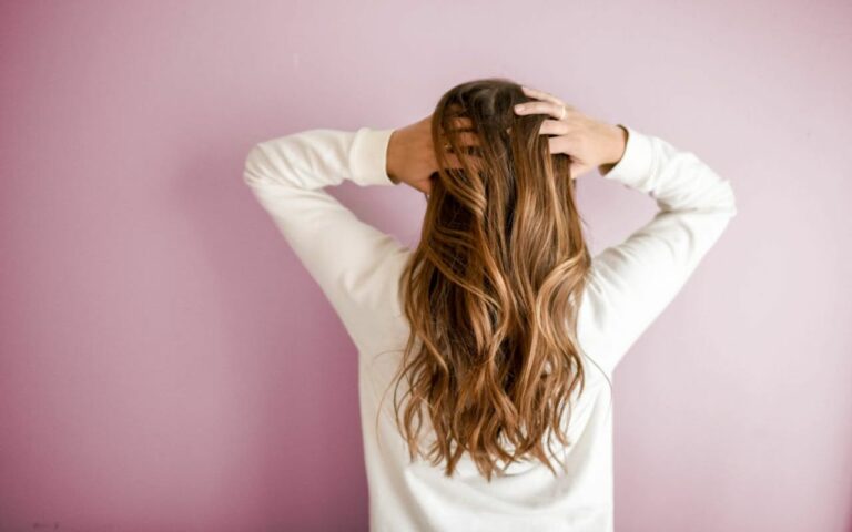 Devojka sa talasastom braon kosom, okrenuta leđima.